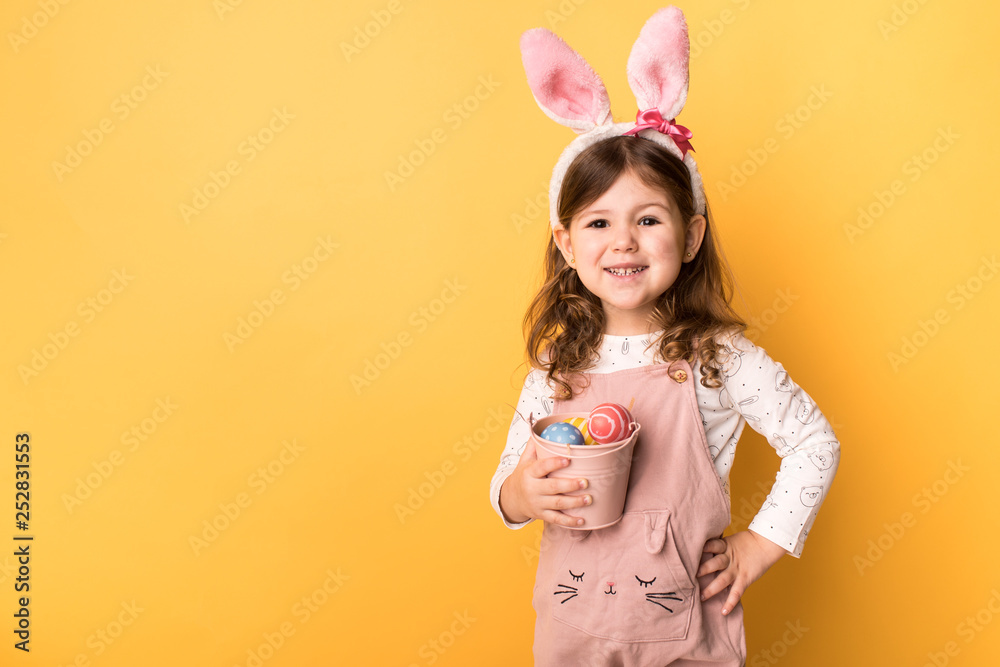 girl with bunny ears holding a bucket of painted eggs