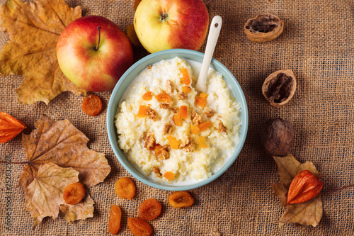 Millet porridge with dried apricots and nuts on the background of autumn leaves