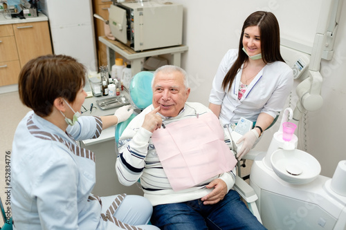 Dentist and nurse making professional teeth checkup male senior patient at the dental office. Dental care for older people. Dentistry, medicine and health care concept