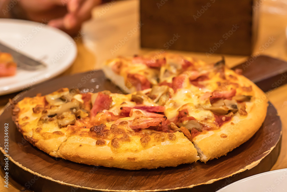 Pizza  ham on the wooden tray is placed on the table.