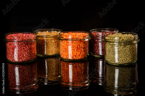 row of small glass jars filled with different colors sea salt