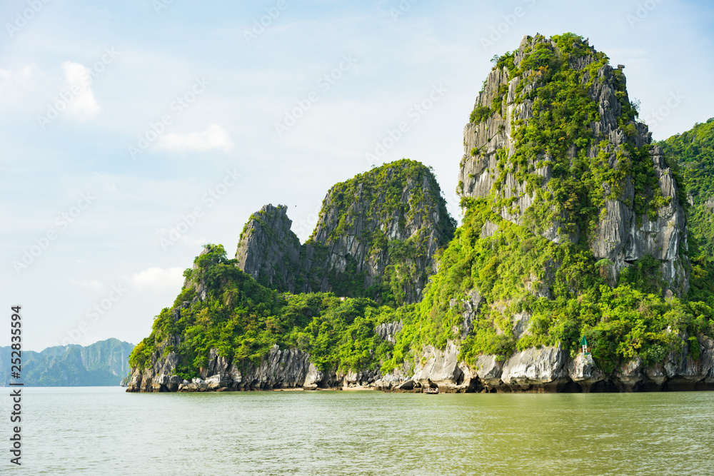 Beautiful travel view in the Halong Bay Vietnam landscape ocean and limestone mountain on blue sky background Beautiful travel view in the Halong Bay Vietnam landscape ocean and limestone mountain on blue sky background