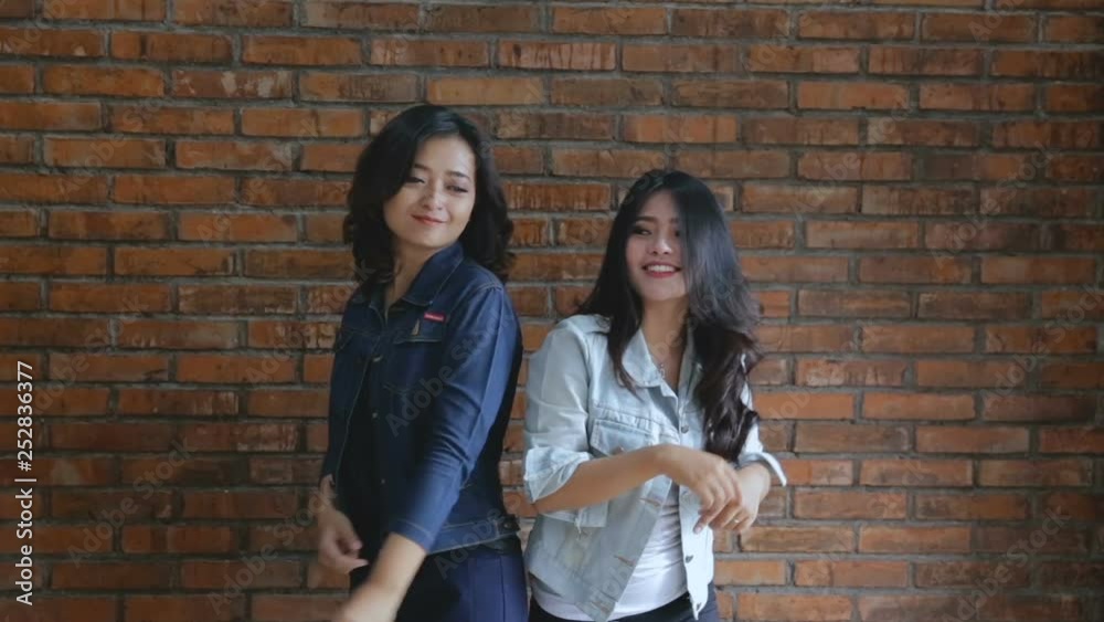 Video of two young happy woman standing over bricks wall Video of two young happy woman standing over bricks wall