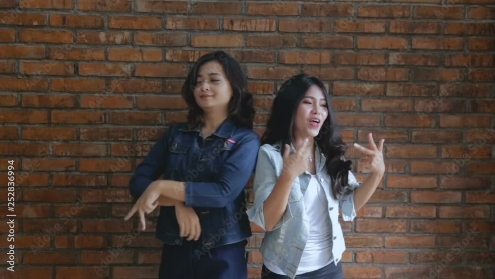 Video of two young happy woman standing over bricks wall Video of two young happy woman standing over bricks wall