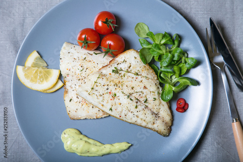 Fried fillet dorado (fish) with tomatoes, lemon and corn salad. Selective focus, close-up.