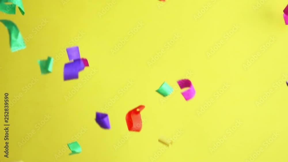 Flying colored confetti in slow motion on yellow background. Party event concept, birthday, happy Flying colored confetti in slow motion on yellow background. Party event concept, birthday, happy