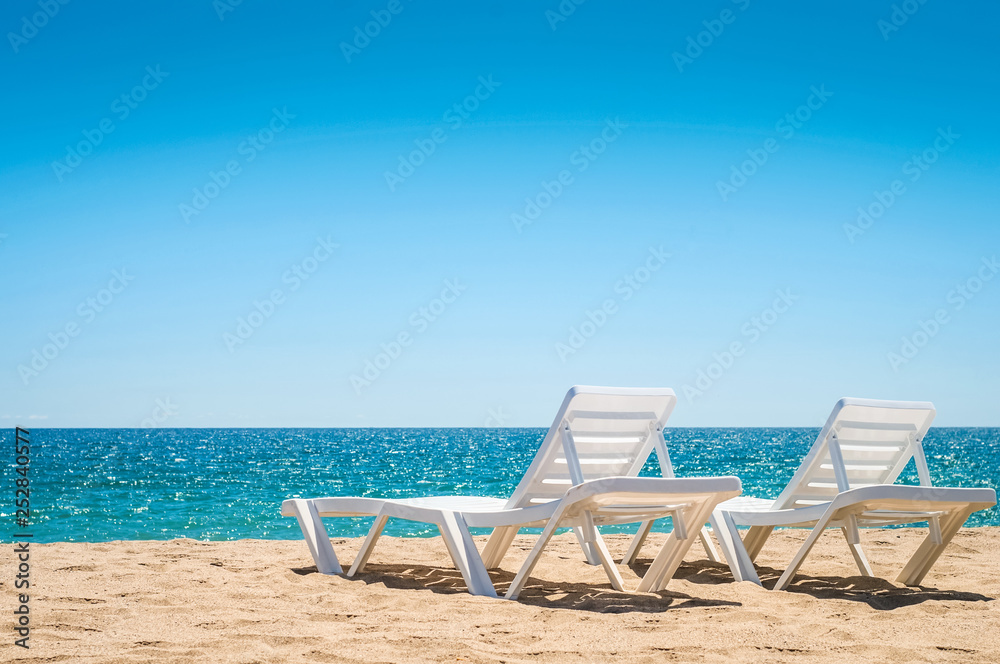 Two chaise-longues on the beach