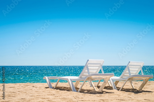 Two chaise-longues on the beach