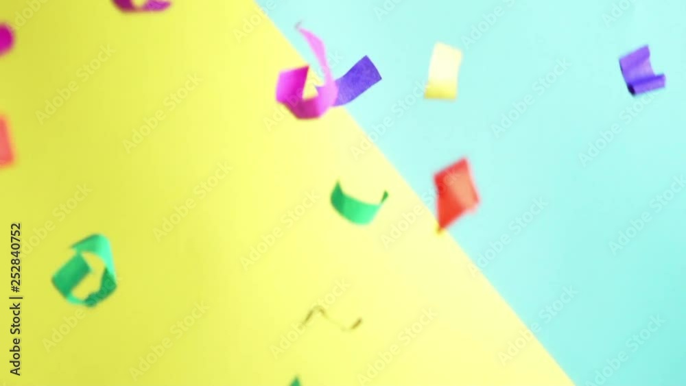 Flying colored confetti in slow motion on yellow-blue background. Party event concept, birthday, happy Flying colored confetti in slow motion on yellow-blue background. Party event concept, birthday, happy