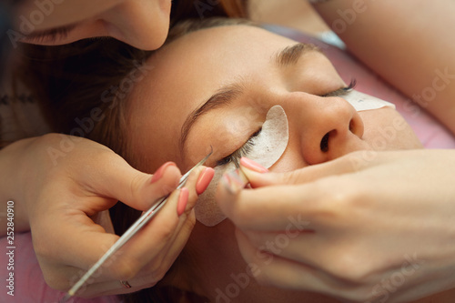 beautician making artificial lashes. eyelash extension procedure.