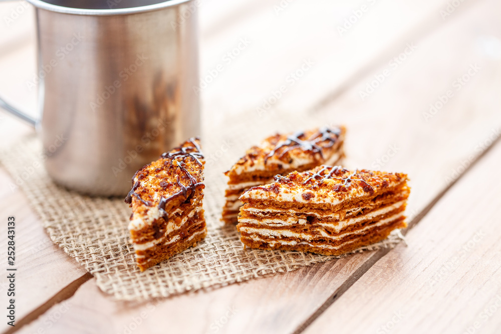 Pieces of cake with layers of cream with a cup of tea on a wooden table