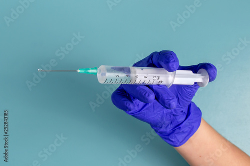 syringe in hand with glove on background