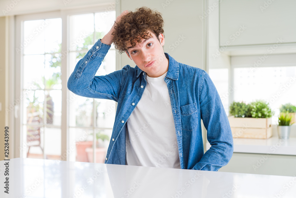 Young handsome man wearing casual denim jacket at home confuse and wonder about question. Uncertain with doubt, thinking with hand on head. Pensive concept.