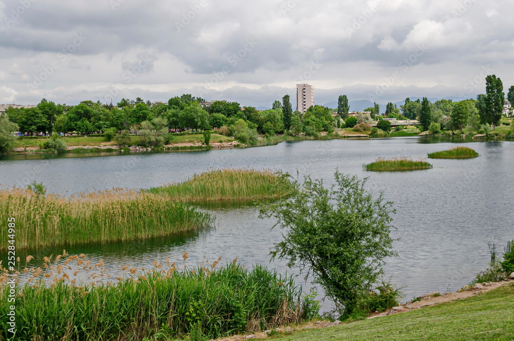 Spring panorama of a part of residential district neighborhood along a lake with green trees, shrubs and flowers, Drujba, Sofia, Bulgaria  