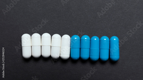 White and blue pills on a black background. Mock-up