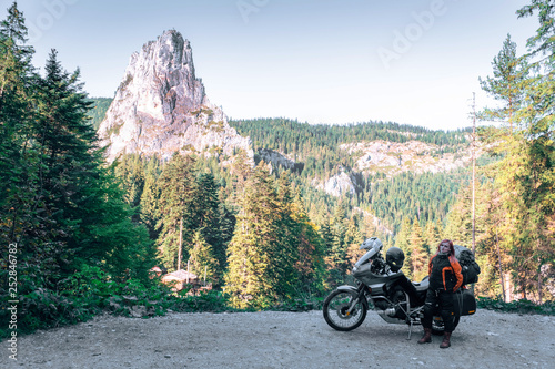 Woman biker and adveture motorcycle on mountain road in Bicaz Canyon  Romania. Travel concept  extreme  vacation in Europe  motorcyclist way  tourism  Cheile Bicazului  Europe. copy space