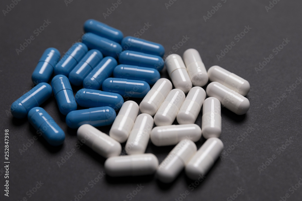 White and blue pills on black background White and blue pills on black background