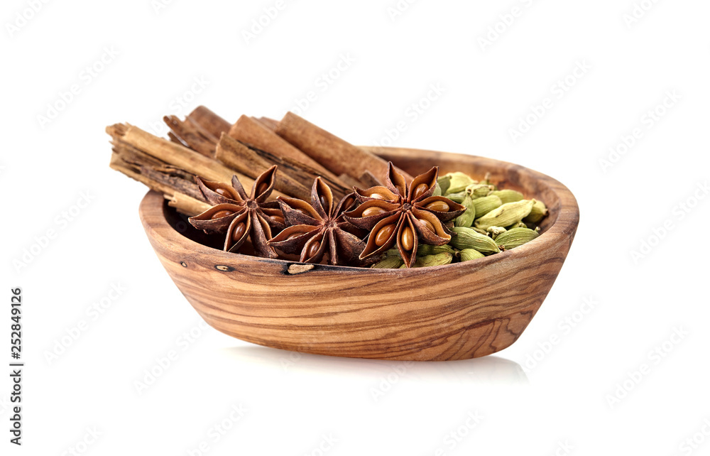 Cardamon, cinnamon, anise in wooden bowl on white background. Spices isolated. Cardamon, cinnamon, anise in wooden bowl on white background. Spices isolated.