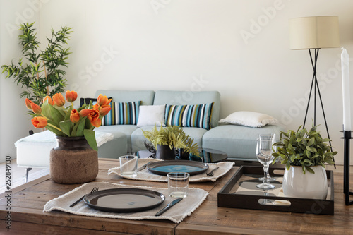 Φωτογραφία Wooden table detail with plates, cutlery and bunch of orange tulips