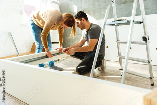 Young couple assembling the bed