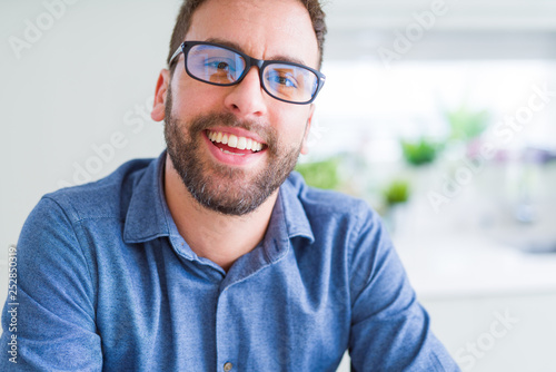 Handsome man wearing glasses and smiling relaxed at camera