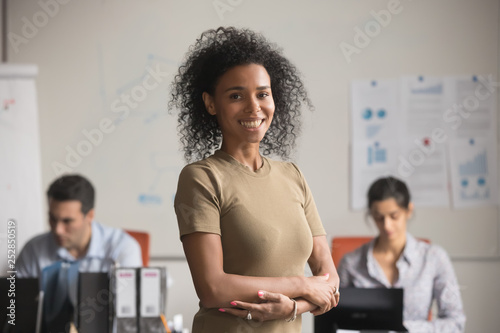 Smiling confident african business woman standing in modern office, portrait