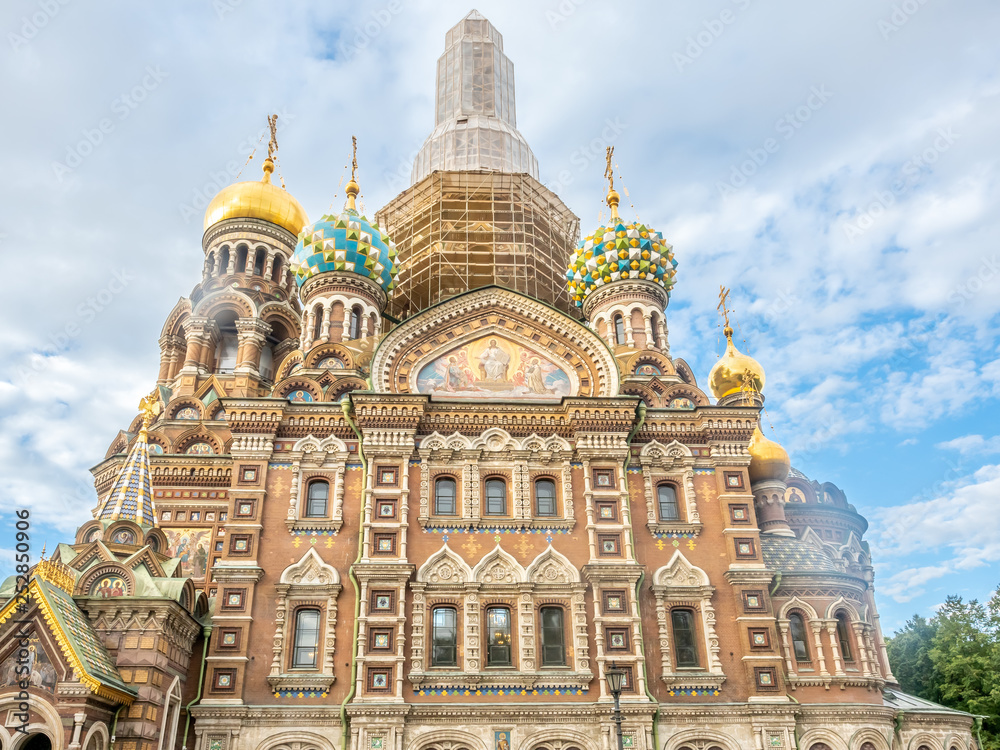 Under construction of the Church of the Savior on Spilled Blood, under cloudy blue sky in summer of Saint Petersburg, Russia