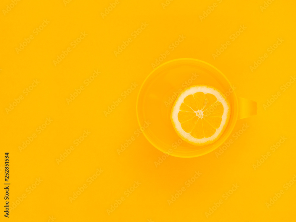 Fototapeta Creative fresh layout. Water with lemon in a yellow mug on a yellow geometric background. Healthy drink, live water, lemonade. Biohacking minimalist concept. Flat lay