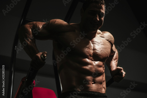 Handsome strong athletic men pumping up muscles workout push ups on bars bodybuilding concept background
