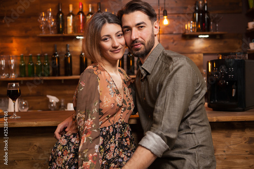 Attractive couple celebrating their aniversary and looking at the camera in vintage pub