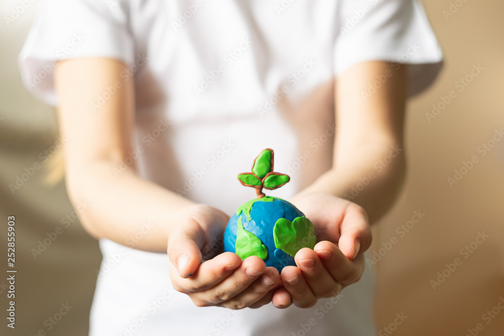 A small globe with trees in the hands of a child. Layout of the planet made of plasticine in children's palms. Concept - obrazy, fototapety, plakaty 