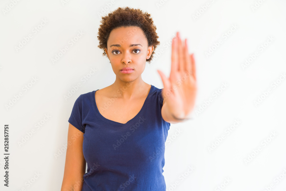 Young beautiful african american woman over white background doing stop sing with palm of the hand. Warning expression with negative and serious gesture on the face. Young beautiful african american woman over white background doing stop sing with palm of the hand. Warning expression with negative and serious gesture on the face.