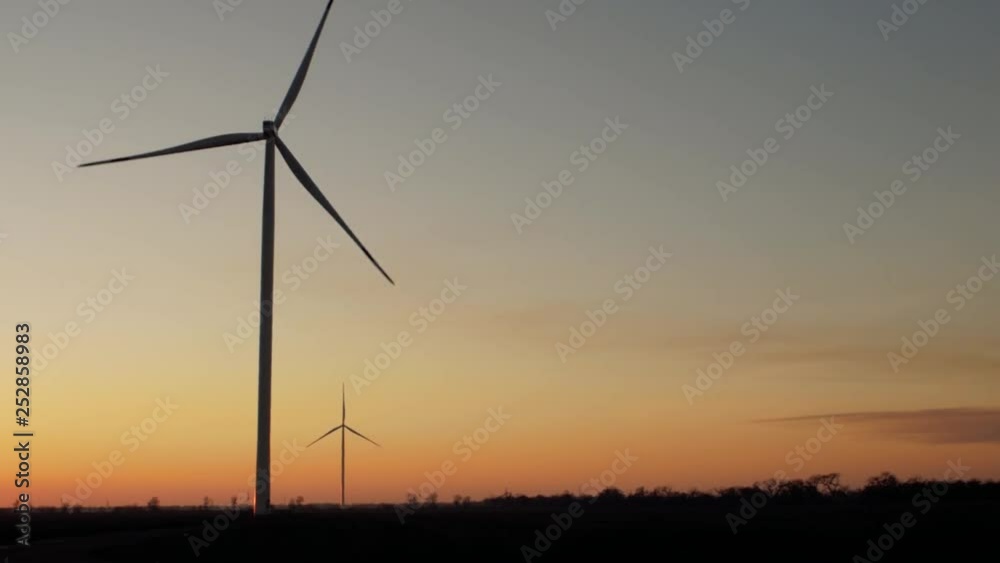 silhouettes of wind turbine generators and trees in a field at sunset silhouettes of wind turbine generators and trees in a field at sunset