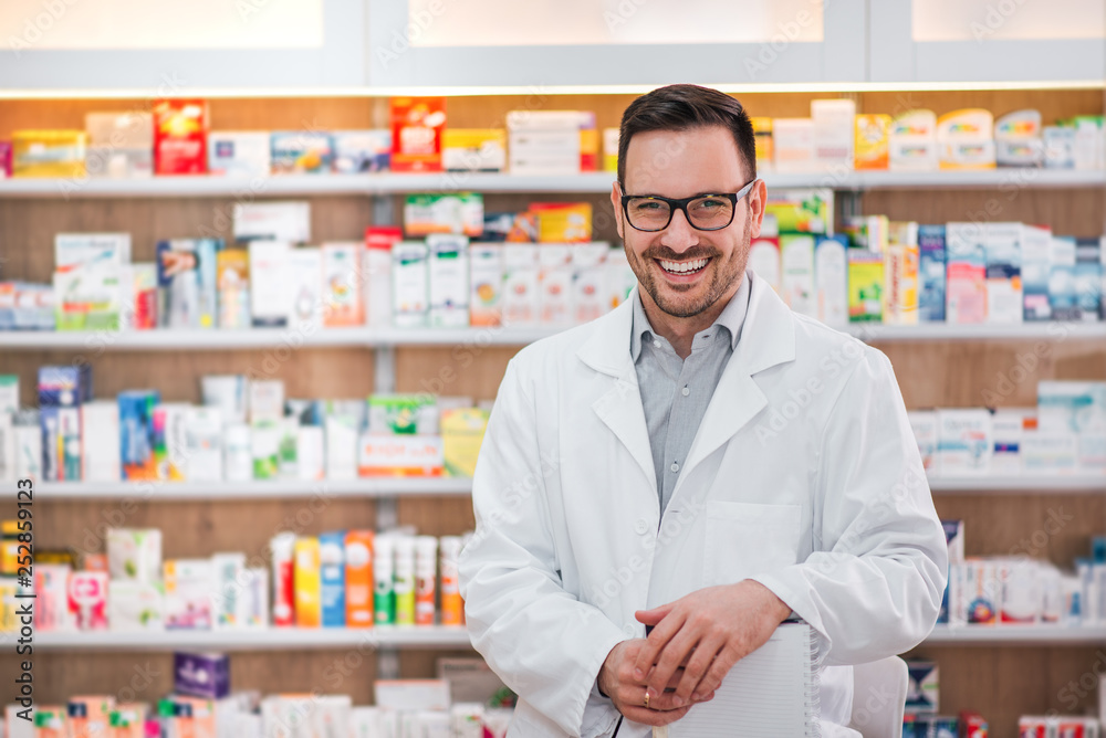 Portrait of a cheerful healthcare worker in white coat at pharmaceutical store.