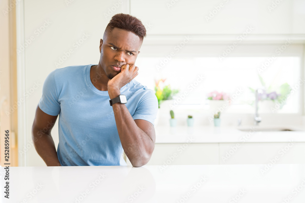 Handsome african american man wearing casual t-shirt at home thinking looking tired and bored with depression problems with crossed arms.