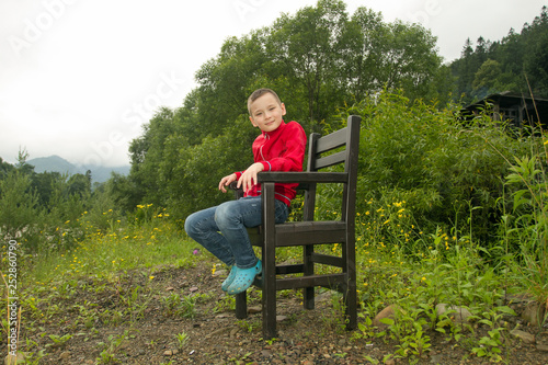 Boy Sitting on Chair in the Forest