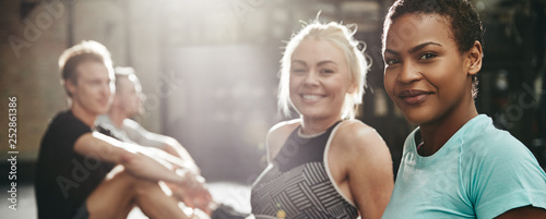 Принти на полотні Smiling women sitting on a gym floor after working out