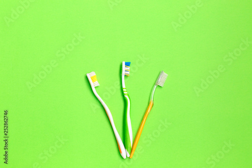 Set of different toothbrushes on green background. Personal care concept. Flat lay.