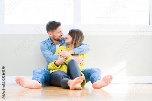 Beautiful young couple in love, kissing and hugging each other sitting on the floor at home