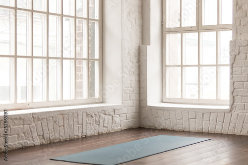Yoga mat on wooden floor in empty room in yoga studio