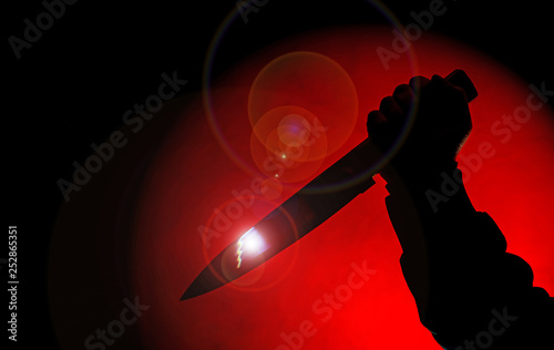 silhouette hand with knife in red spotlight on black background,spooky knife in the darkness