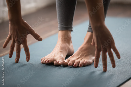 Woman practicing yoga, uttanasana pose, Head to knees close up