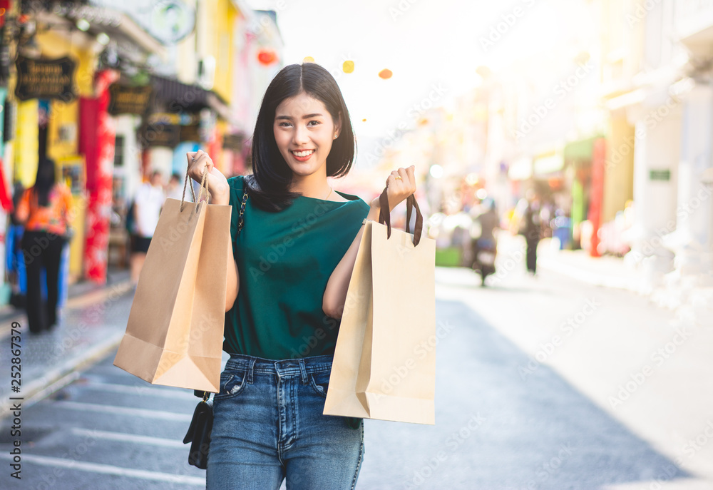 Asian women are addicted to shopping or shopaholic shopping in the old town with colorful paper shopping bags during the discount season with copy space and blur city or tourist background, Soft tone. Asian women are addicted to shopping or shopaholic shopping in the old town with colorful paper shopping bags during the discount season with copy space and blur city or tourist background, Soft tone.