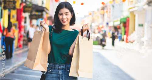 Asian women are addicted to shopping or shopaholic shopping in the old town with colorful paper shopping bags during the discount season with copy space and blur city or tourist background, Soft tone.