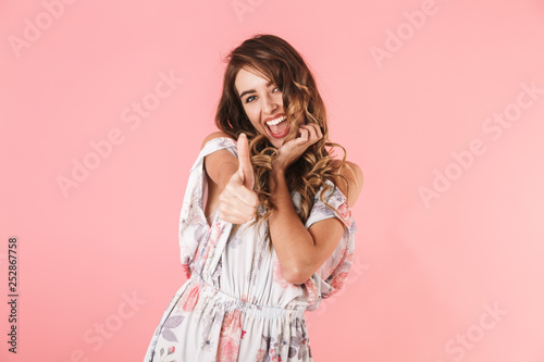 Image of joyous woman 20s with long hair wearing dress showing thumbs up