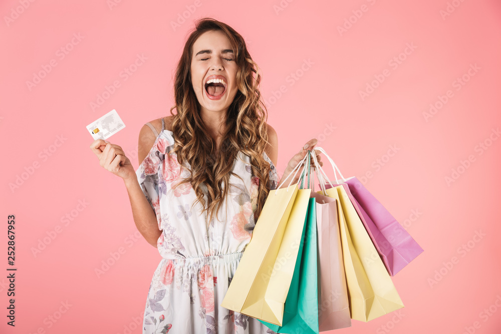 Image of adorable woman 20s in dress holding credit card and colorful shopping bags
