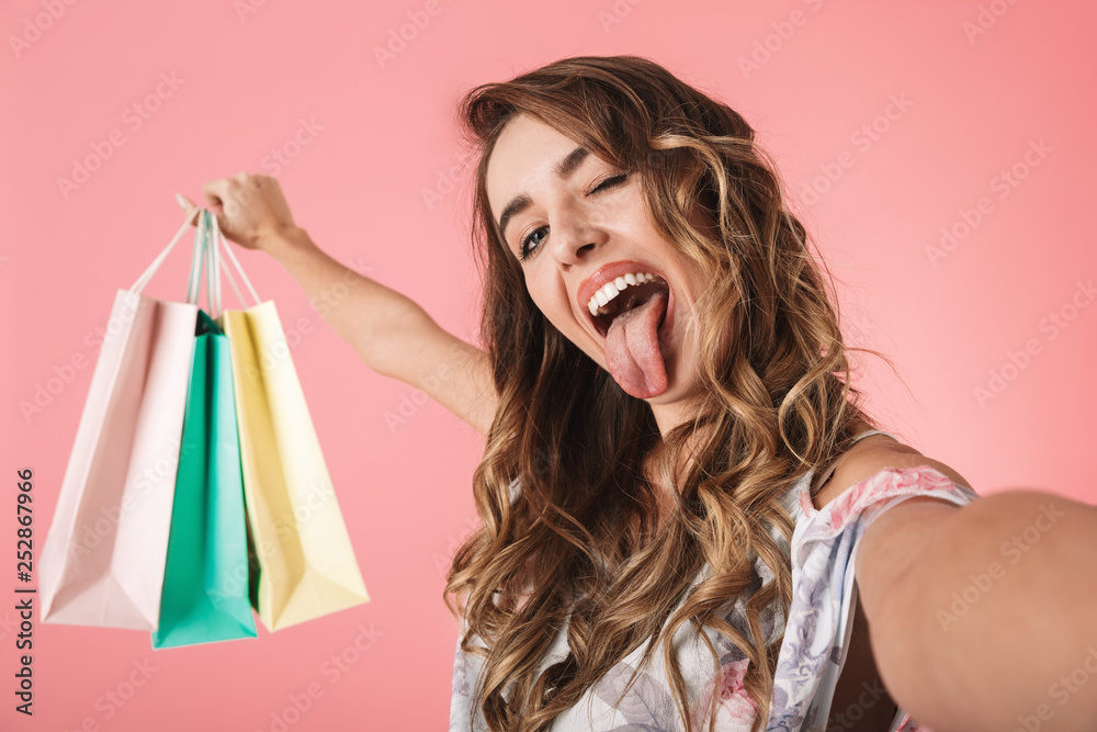 Image of stylish woman 20s in dress holding colorful shopping bags and taking selfie Image of stylish woman 20s in dress holding colorful shopping bags and taking selfie