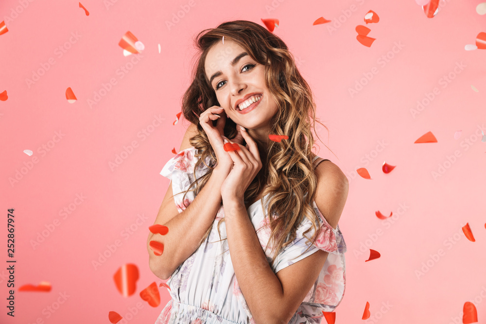 Image of stylish woman 20s wearing dress smiling and standing under falling confetti Image of stylish woman 20s wearing dress smiling and standing under falling confetti