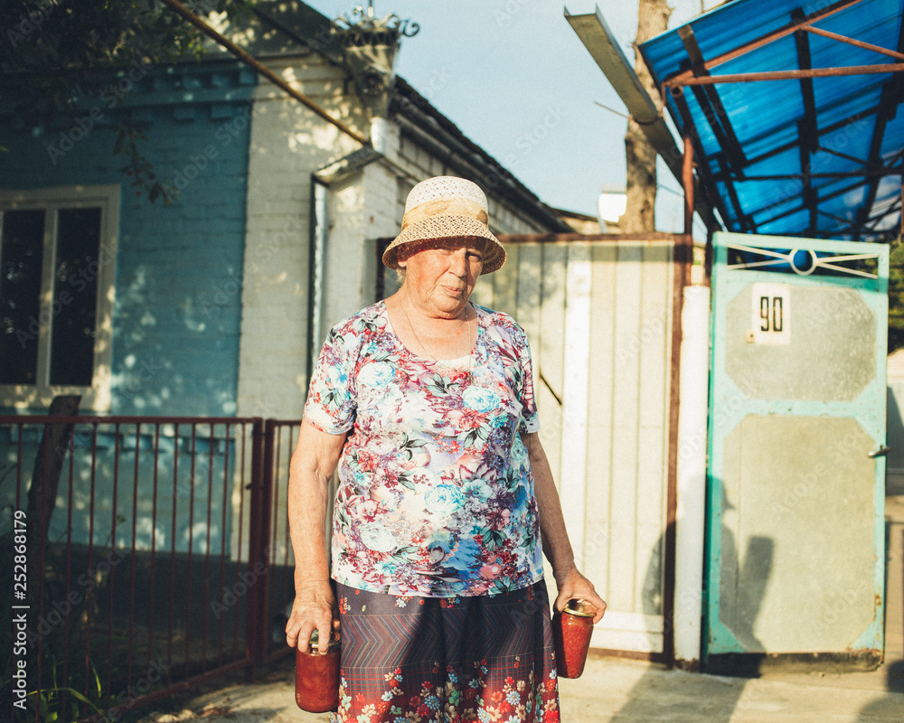 An elderly pensioner holding in her hands homemade preserves