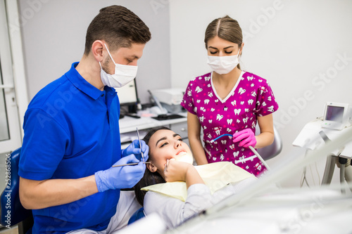 Young woman patient at dentist  holding hand on cheek  showing pain in dental clinic